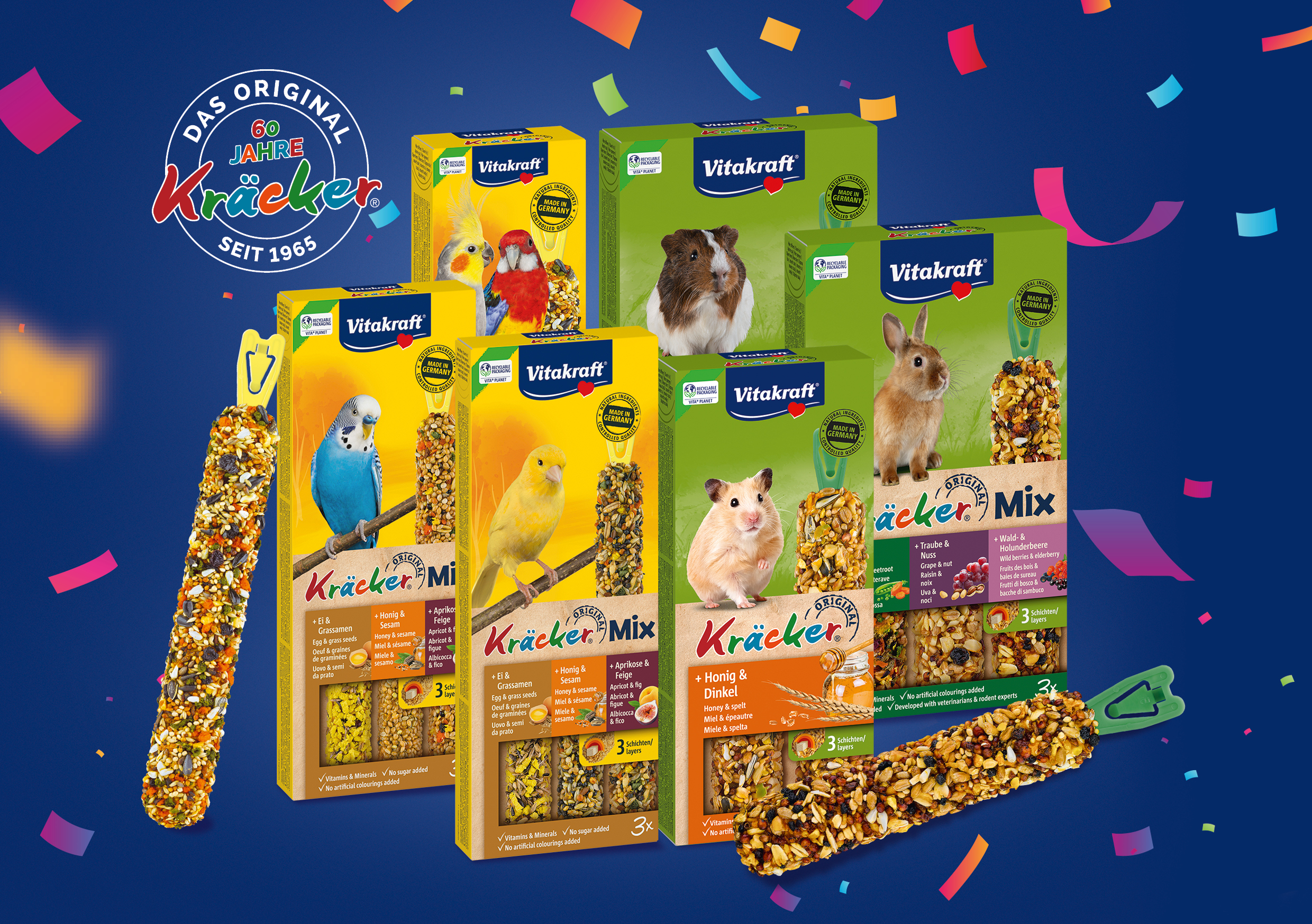 Verschiedenen Kr&auml;cker-Produkte von Vitakraft f&uuml;r V&ouml;gel und Nager auf blauem Hintergrund mit Konfetti und St&ouml;rer "60 Jahre Kr&auml;cker"